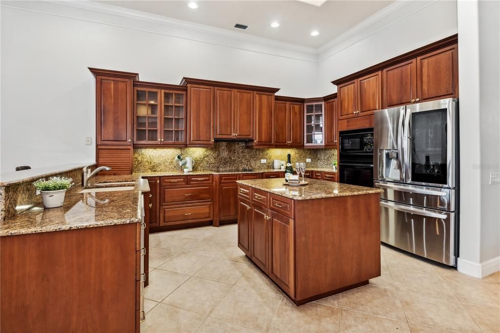 Spacious and open kitchen with cherry cabinets plus granite counters and backsplash.