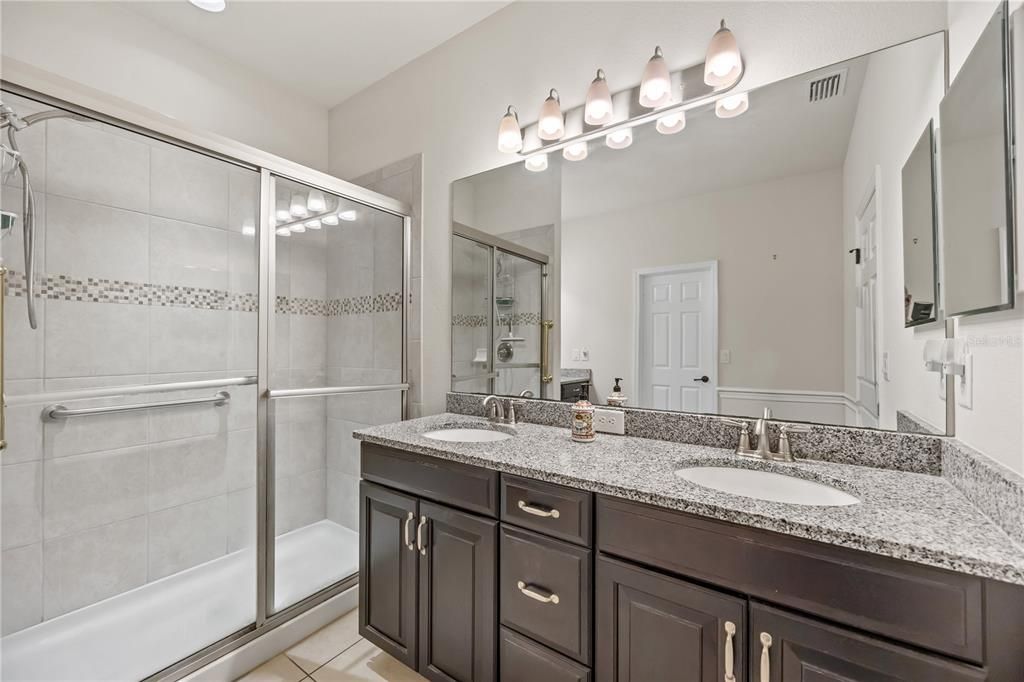 Ensuite bathroom features a double vanity with timeless dark wood cabinetry and granite countertops