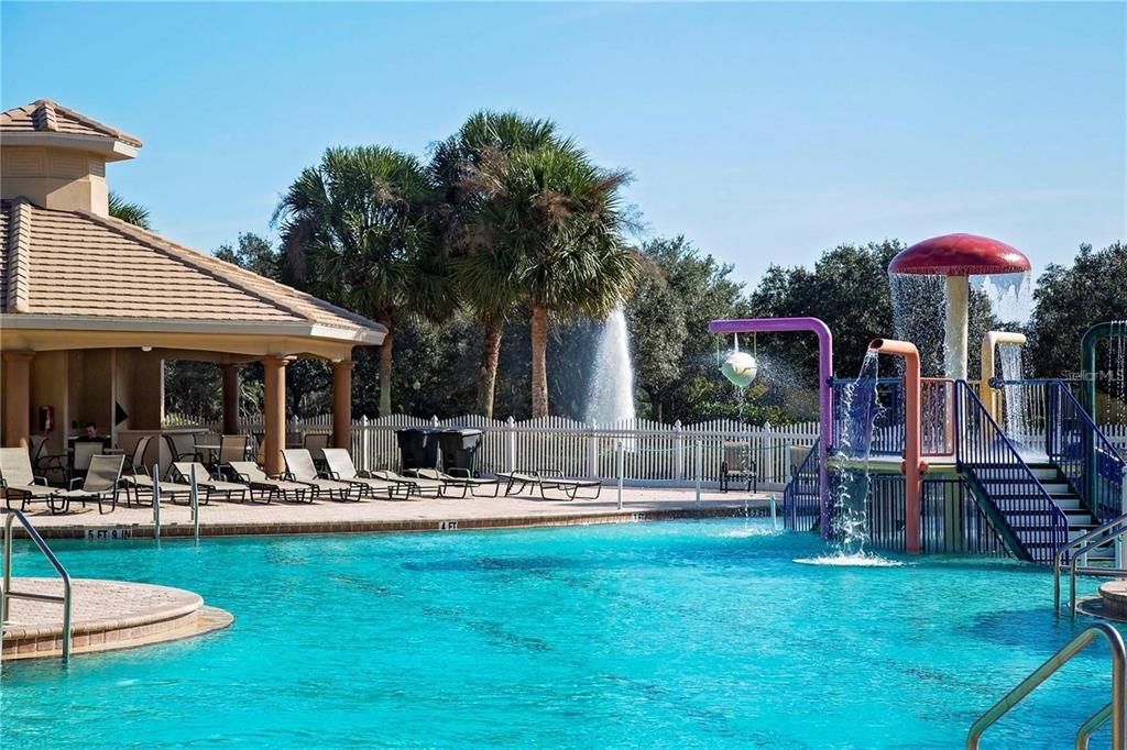 Community East pool with water slide, splash pad, heated pool and spa, outdoor covered lanai brick paver area for lounging pool side