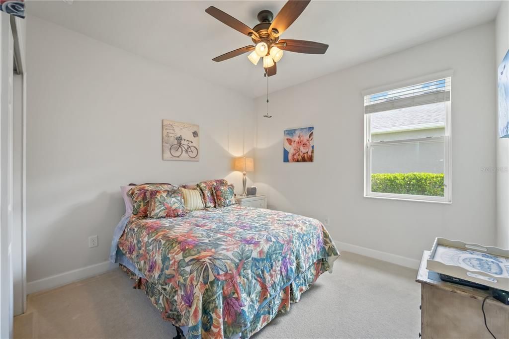 Second bedroom with spacious storage closet, ceiling fan and carpet flooring