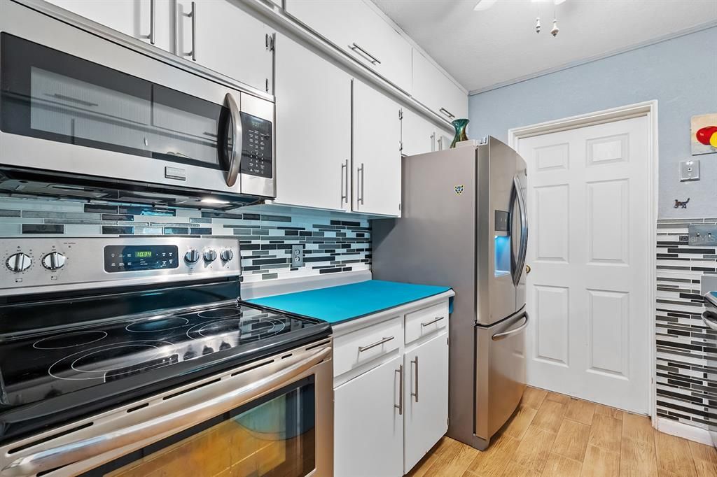 Kitchen has stainless steel appliances, tile backsplash, ceiling fan, and tile floors.