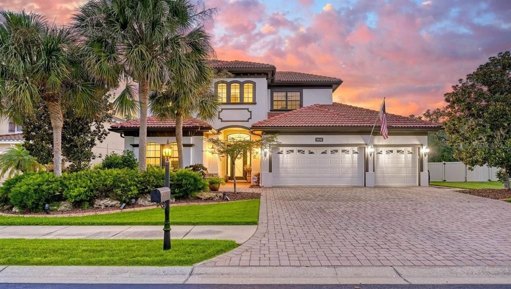 Front elevation featuring the large paver driveway, 3 car garage, and stunning landscaping.