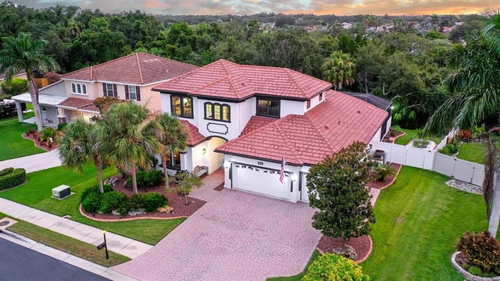 Aerial of the front elevation featuring the large paver driveway, 3 car garage, and stunning landscaping.