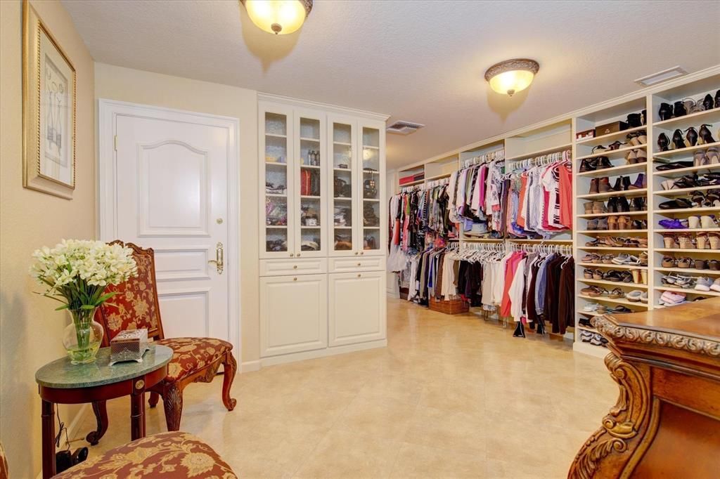 Her walk-in closet has an additional locked jewelry closet and has a second level reached by a stairway leading to a gift-wrapping room with vaulted ceiling, built in cabinets, granite desk, wood drawers and cupboards