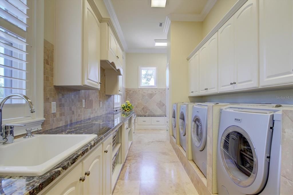 Spacious laundry and mud room, with built in cabinetry, granite, utility sink, floor mop sink, 2 Bosch washers, 2 Bosch dryers,  bins for laundry baskets, double hanging closet & linen closet