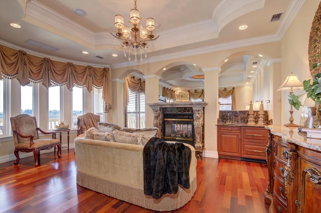 Master Suite sitting room is inviting with a wet bar with granite, cherry wood and cherry paneled 2 drawer refrigerator, a double-sided gas fireplace