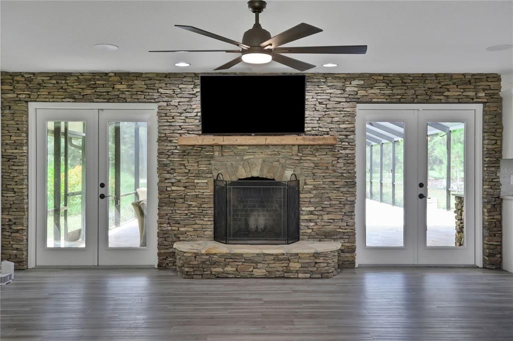 Double French Doors with Wood-burning Fireplace and 55" TV leading out to Pool