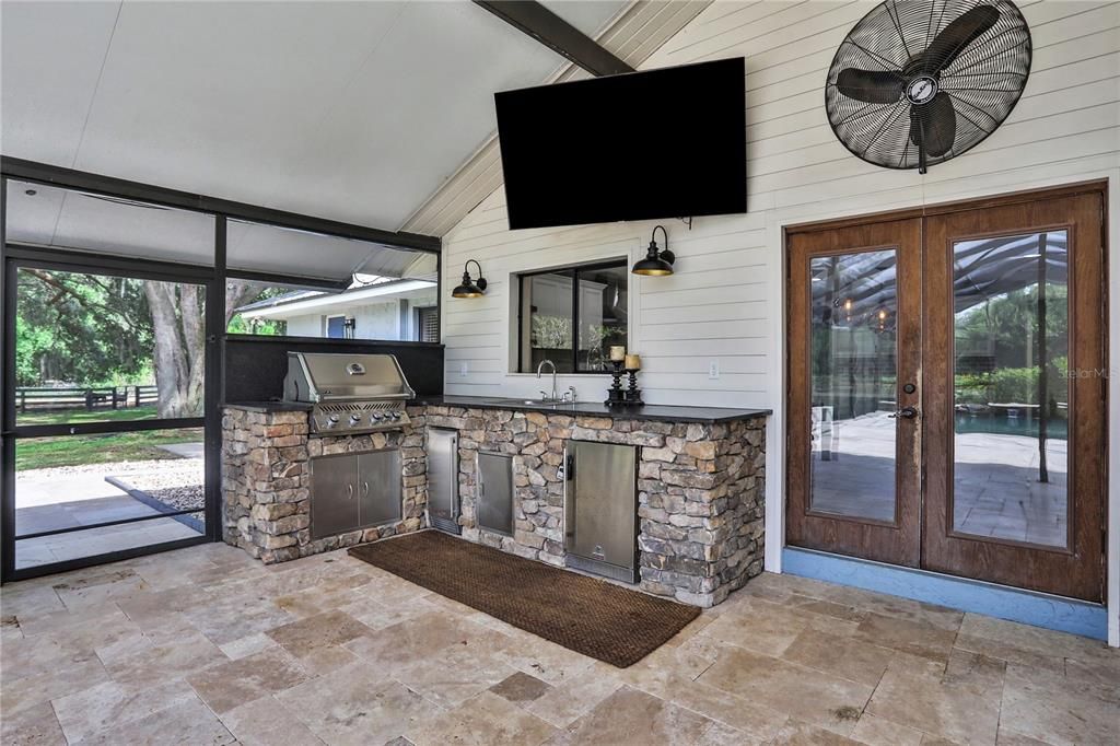 Outdoor Kitchen with Napoleon Grill, Sink, Ice-Maker, Mini-Fridge, 75" TV, and 2 large Oscillating Fans to keep cool during the Summer months.