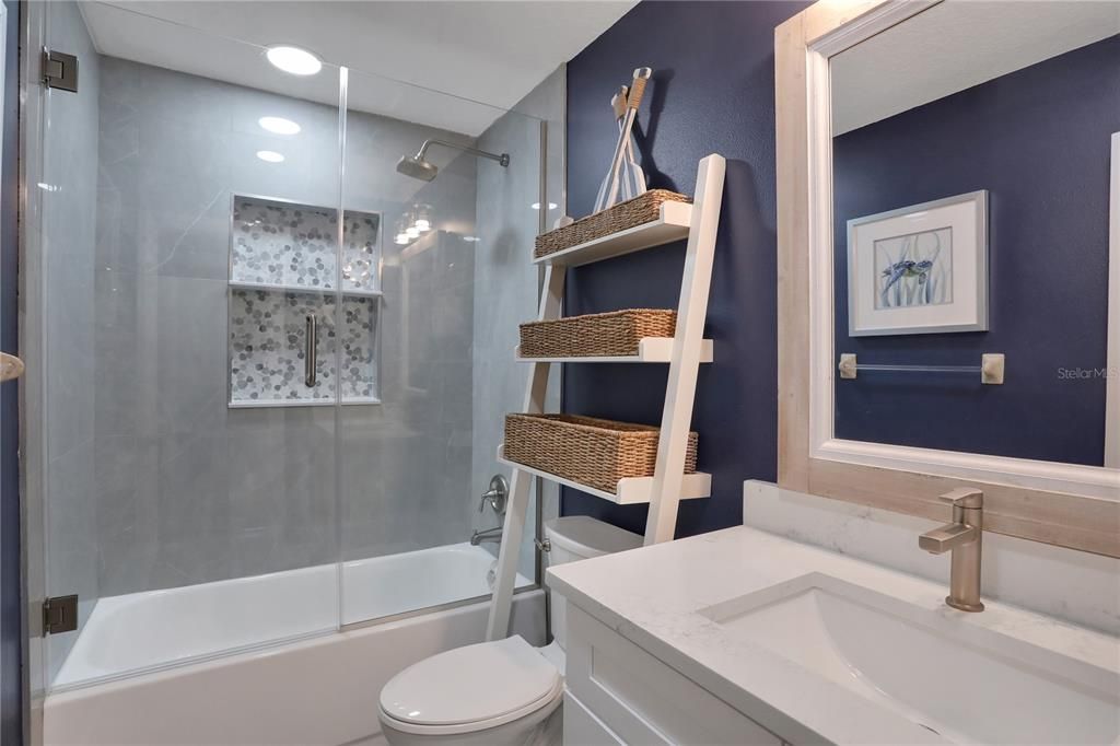 Guest Bathroom with a tub and shower enclosed with frameless glass