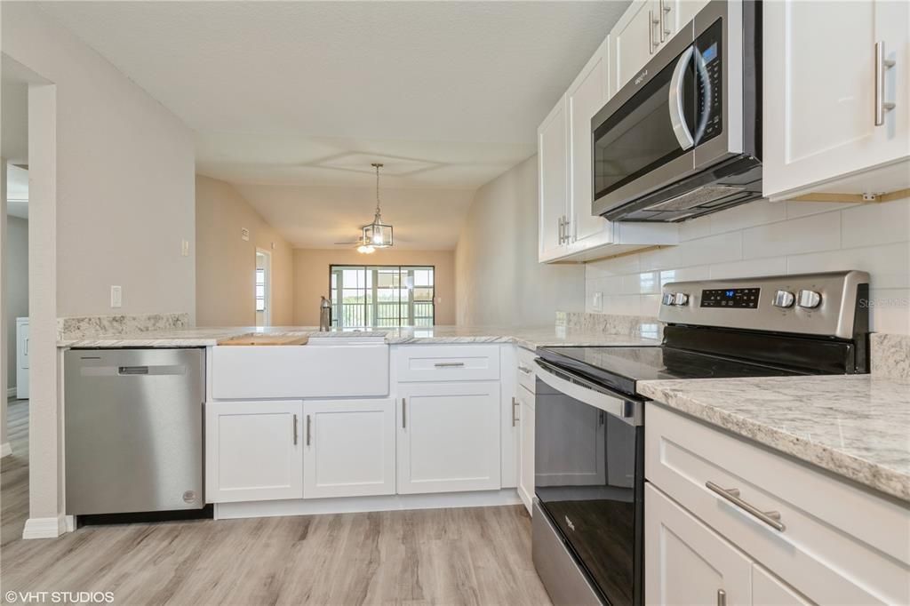 farm sink, granite counters, new flooring, fixtures too, looking toward dining area/living room beyond