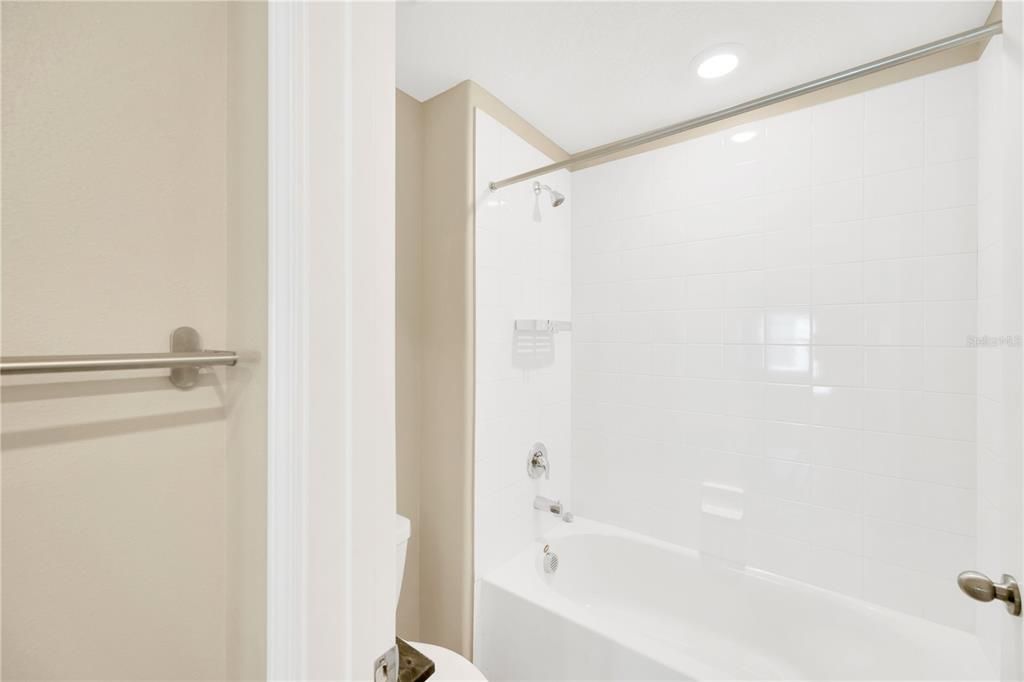 Bathroom has a separate tub/shower combo and toilet tucked away from the sinks in a separate room.