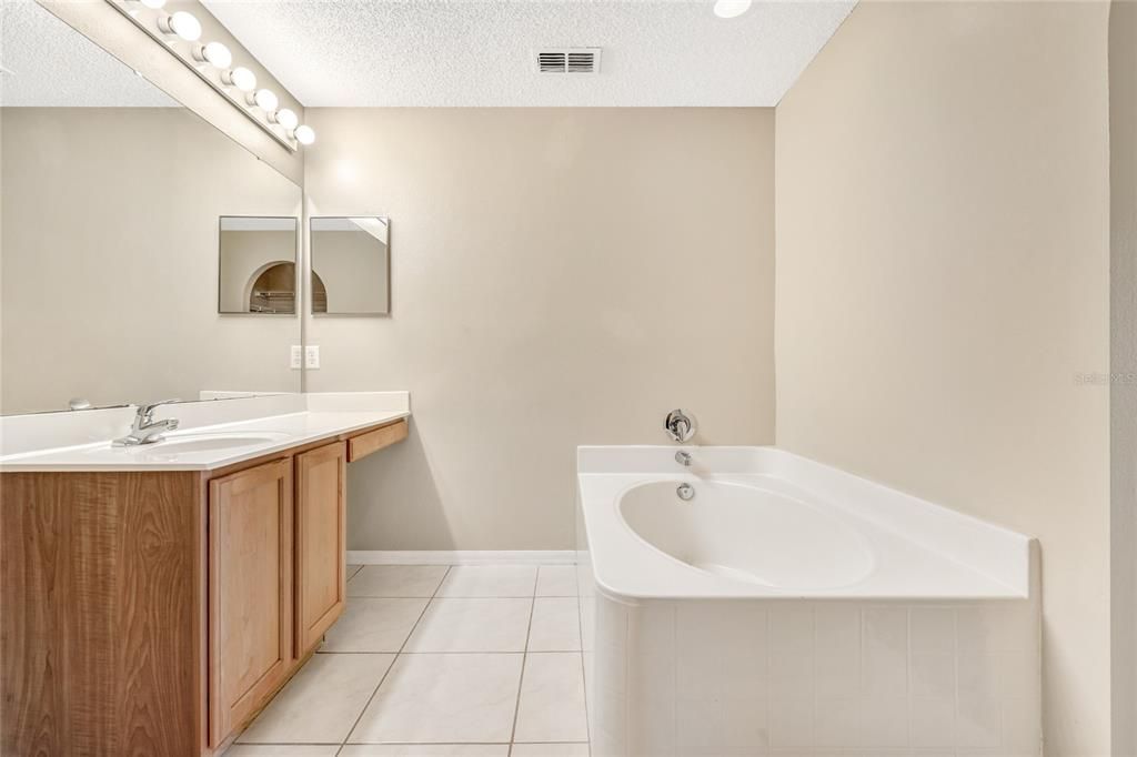 bathroom with single sink vanity area, a tub and a separate toilet