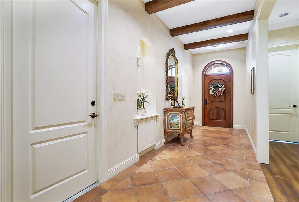 Architectural arched niches and exposed wood beams create a stunning and inviting entry foyer.  Ten foot ceilings and arched paneled doors throughout.  Door to the right enters into the double car garage.