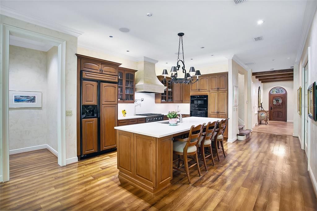 View of Kitchen towards the front foyer and door.  The range hood is fabricated of Scagiola stone by Thierry Francois.  New Quartz counter tops and tile backsplash