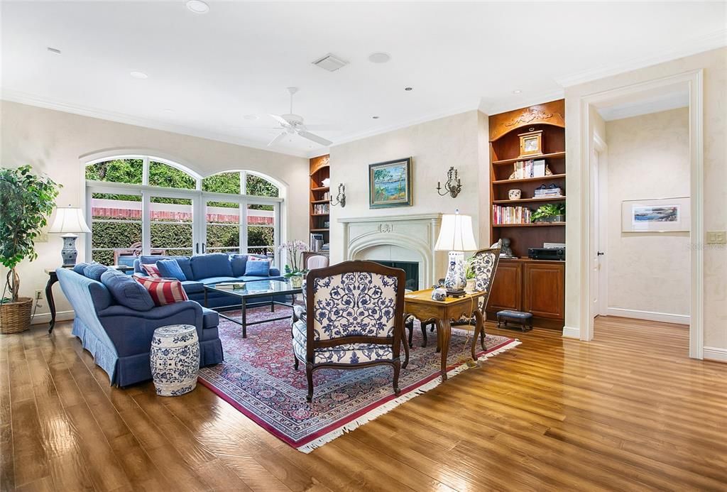 The Great room sitting area features a beautiful French designed fireplace by Thierry Francois fabricated of Scagiola stone flanked by built-in bookcases. The open floor plan is enhanced by the beautiful doors with arched transoms that line the room.