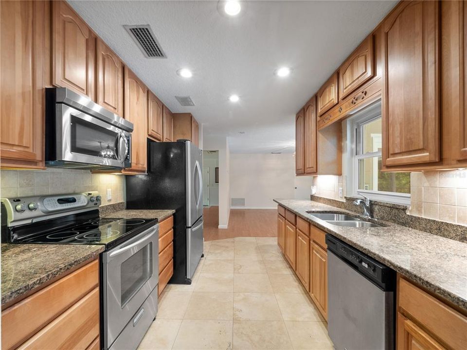 Travertine flooring in updated kitchen with granite tops and views of the pool.