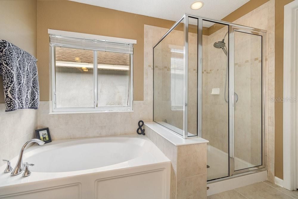 Primary Bathroom with dual sinks, Corian counters, Garden tub with separate shower stall, and tiled flooring.