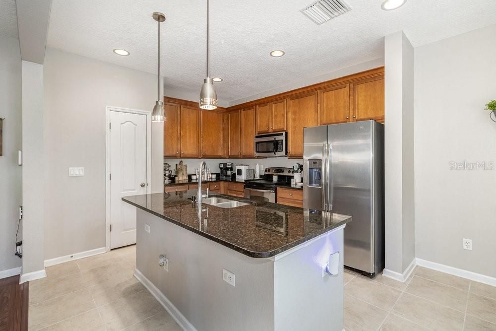 Open concept Kitchen with Granite counters and breakfast bar with Pendent lighting, Stainless Steel appliances, recessed lighting, and tiled flooring.