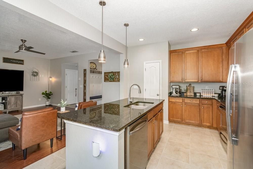 Open concept Kitchen with Granite counters and breakfast bar with Pendent lighting, Stainless Steel appliances, recessed lighting, and tiled flooring.