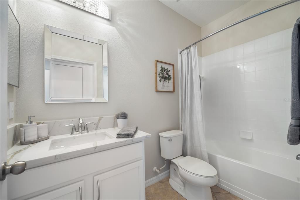 Guest bath 1, level 4 quartz countertops, white and bright with new light fixtures and mirror