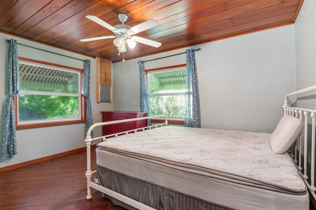 Virtually staged - double doors from the Primary Ensuite Bedroom to screened lanai overlooking waterfront and mature landscaping.