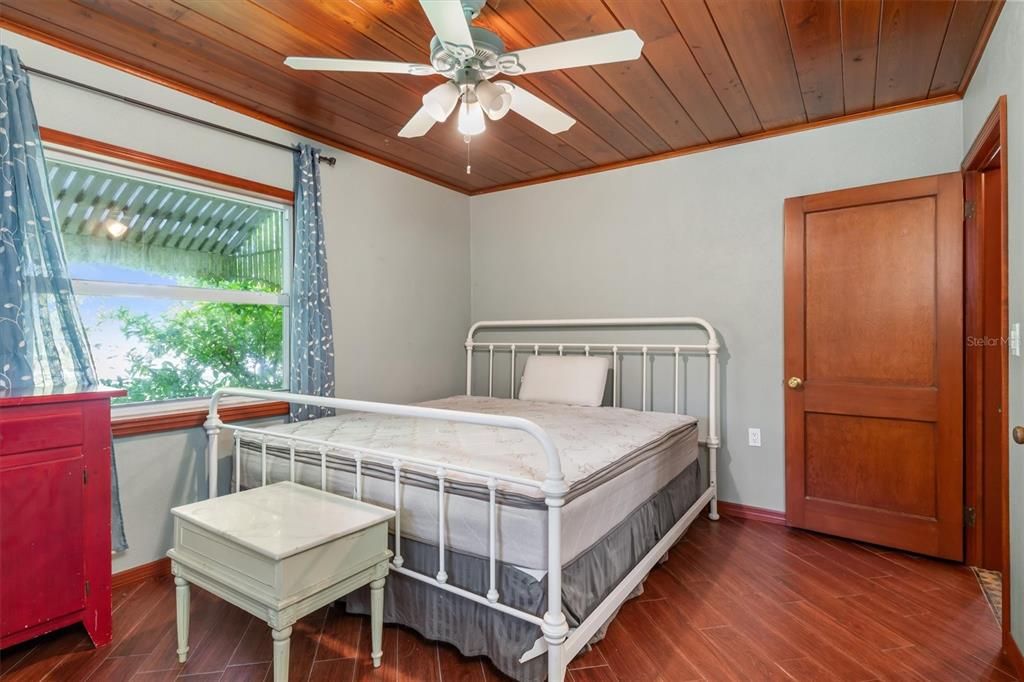 Primary Bedroom with new windows and French doors leading to wrap-around screened lanai and waterfront.  Built in storage.