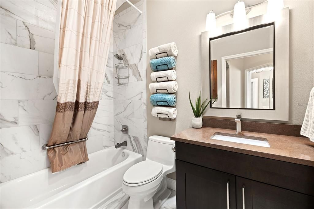 The guest bathroom is equally impressive with a gorgeous, tiled shower/tub combo and a quartz countertop vanity.