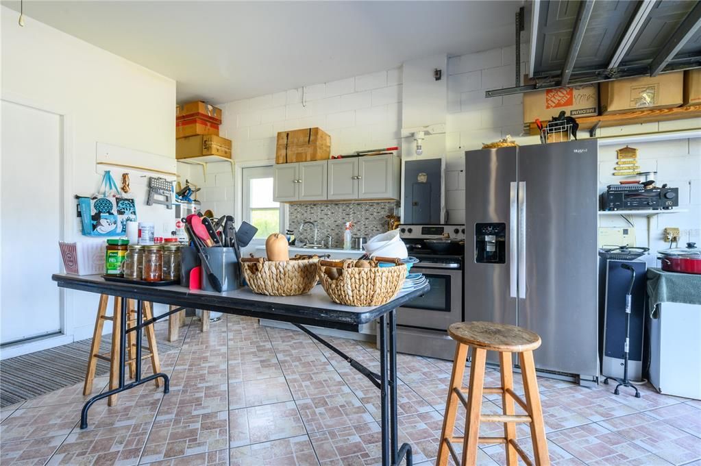 This 2 car garage is filled with functionality.  Complete kit with cabinets, sink and plenty of room for Range and Refrig. (Range and Ref and chest freezer do not convey). All Tiled Floors too.