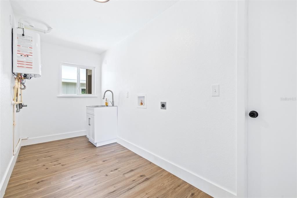 Laundry room with gas tankless water heater and sink