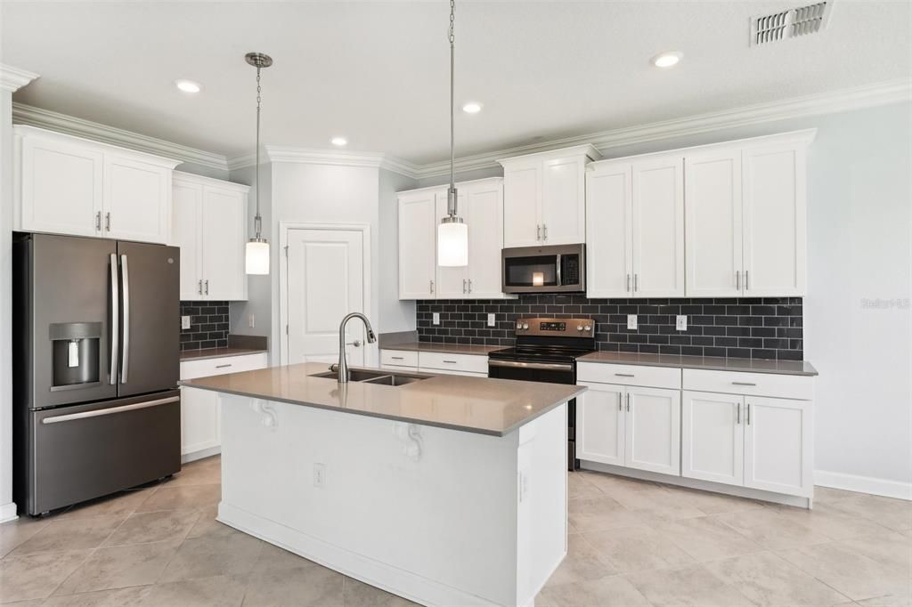 The Kitchen has STONE COUNTERTOPS, an OVERSIZED ISLAND, STAINLESS STEEL APPLIANCES, UPGRADED CABINETRY and BEAUTIFUL TILE BACKSPLASH.