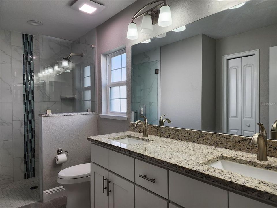 Primary Bathroom with beautiful shower, decorative listello, double vanity and granite countertops