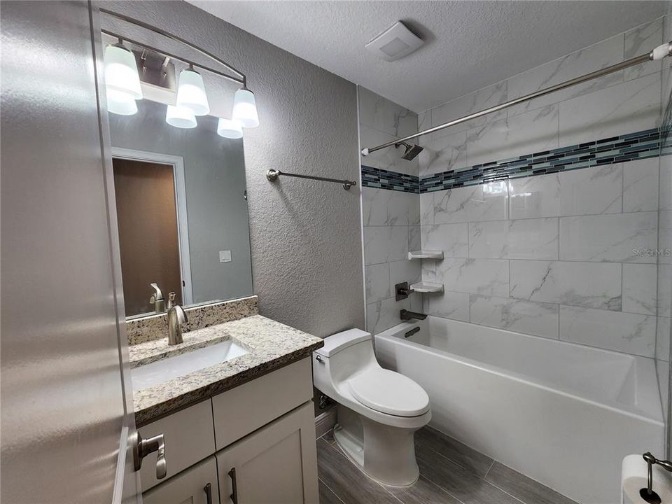 Hall Bathroom with deep tub and shower combo, granite and tiled shower surround