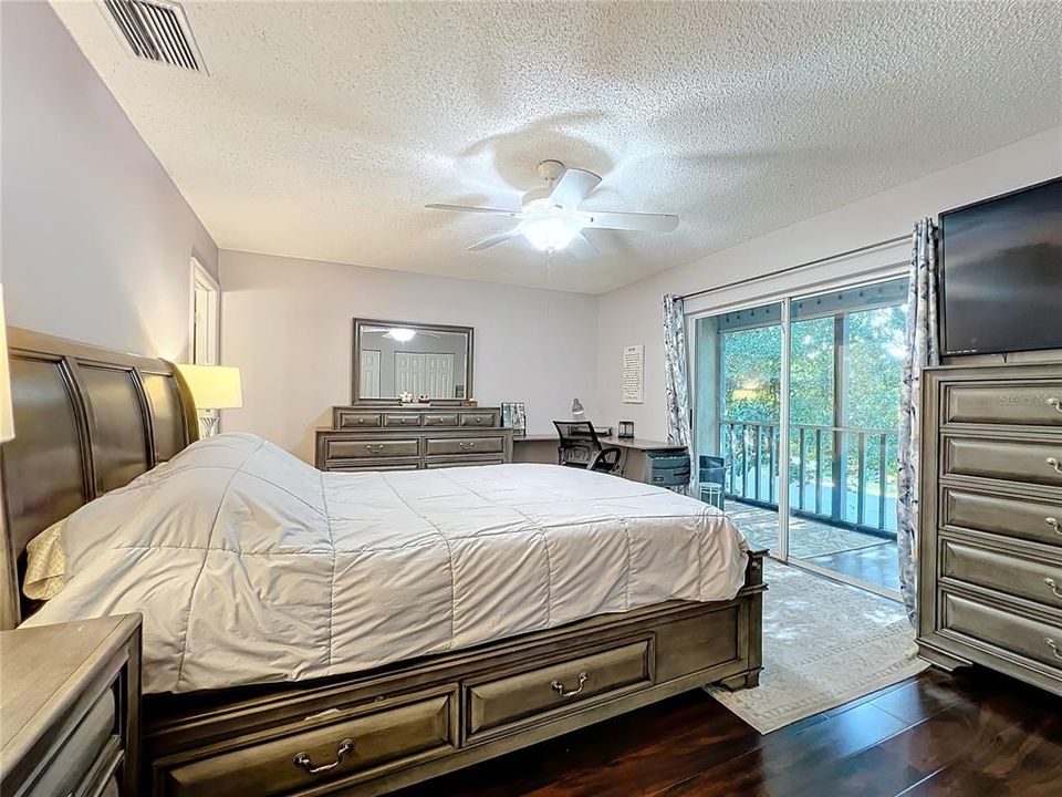 Primary bedroom with sliding glass doors to private screened balcony.