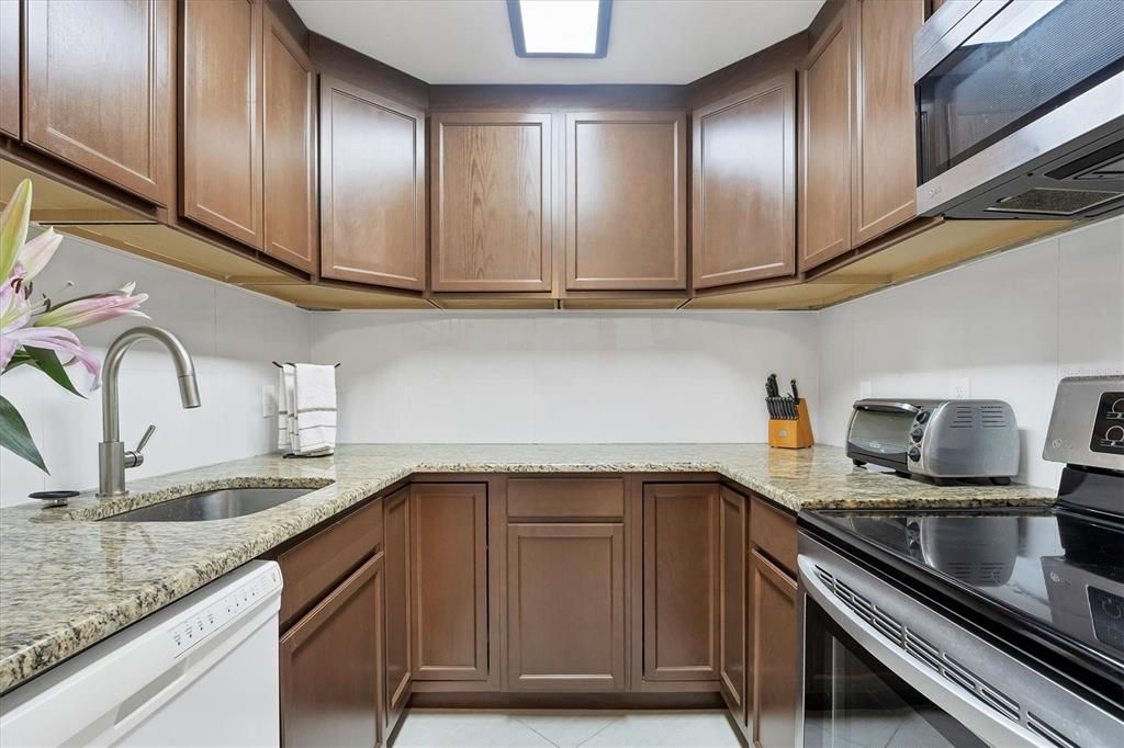 kitchen has granite counter tops and large white tile backsplash