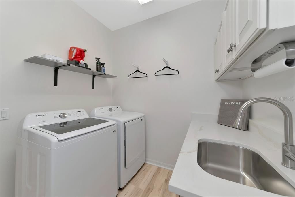 Organized laundry room with quarts countertops and cabinets.