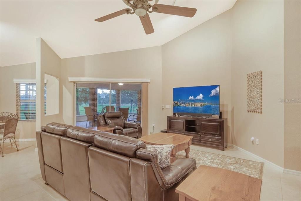 Living room featuring vaulted ceilings, ceramic tile, and sliding glass doors to the covered screened-in lanai.