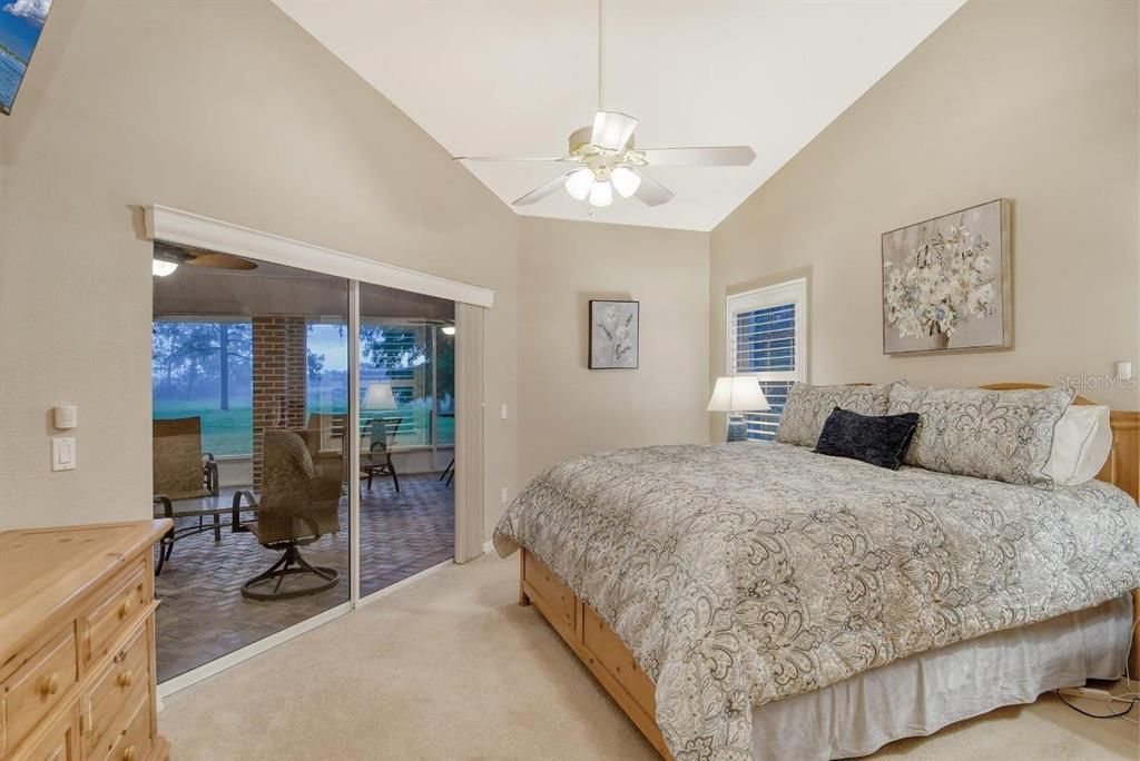 Owners suite featuring dual walk-in closets, sliding glass doors to the covered screened-in lanai, and ensuite bathroom.