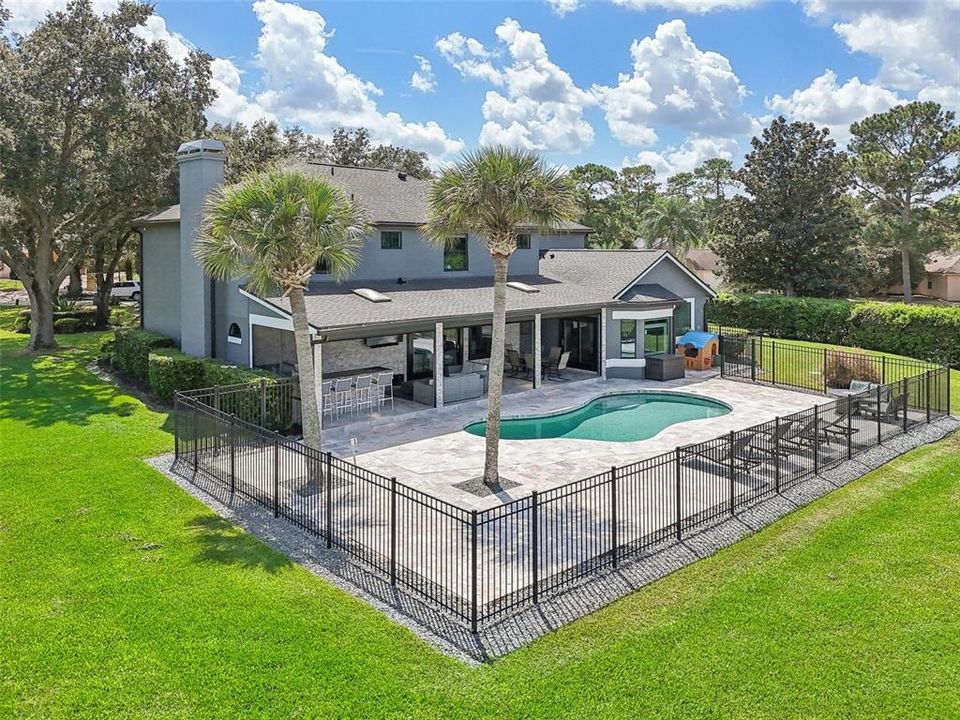 Fenced open air pool with extended travertine paved deck