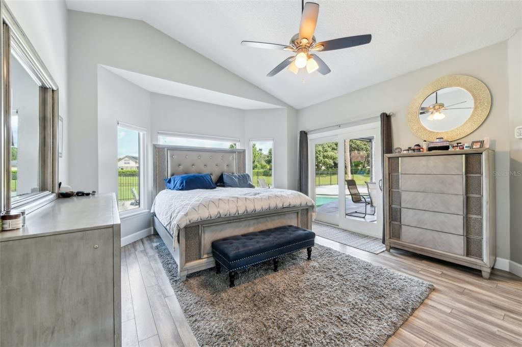 Primary suite with large windows and sliding glass doors out to the covered lanai and pool