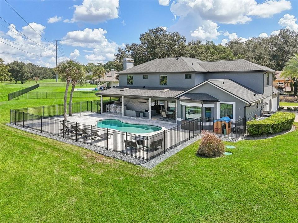 Fenced open air pool with paved deck, large covered lanai and summer kitchen is perfect for entertaining