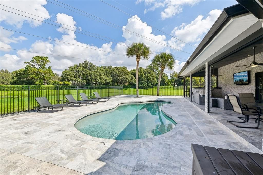 Large travertine pool deck along with spacious covered lanai