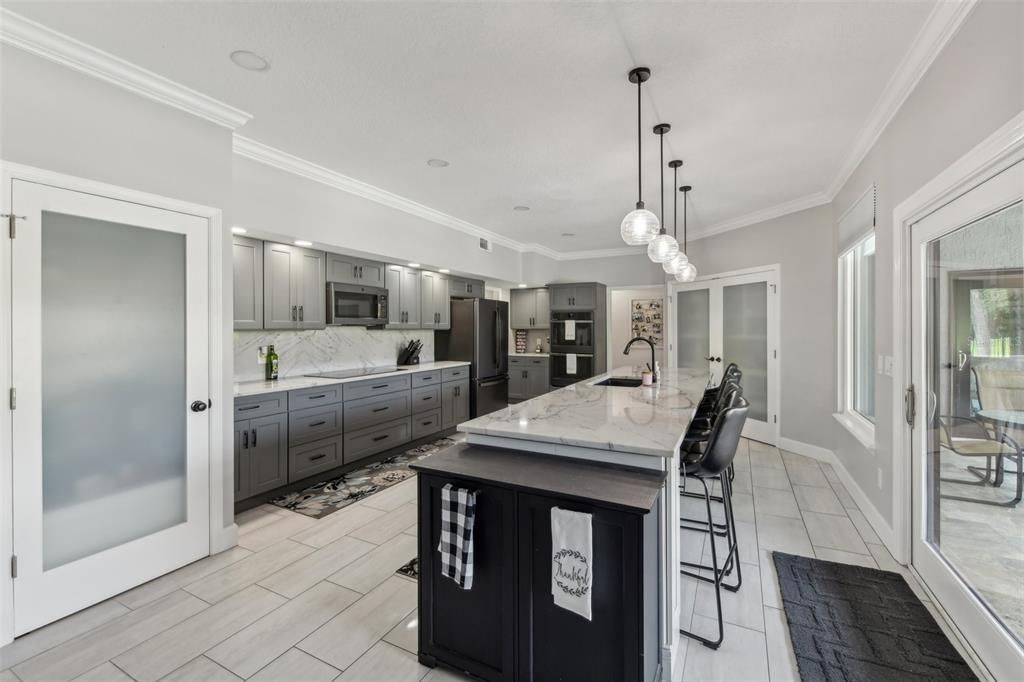 Kitchen includes a large pantry with modern glass doors and wood-look tile floors