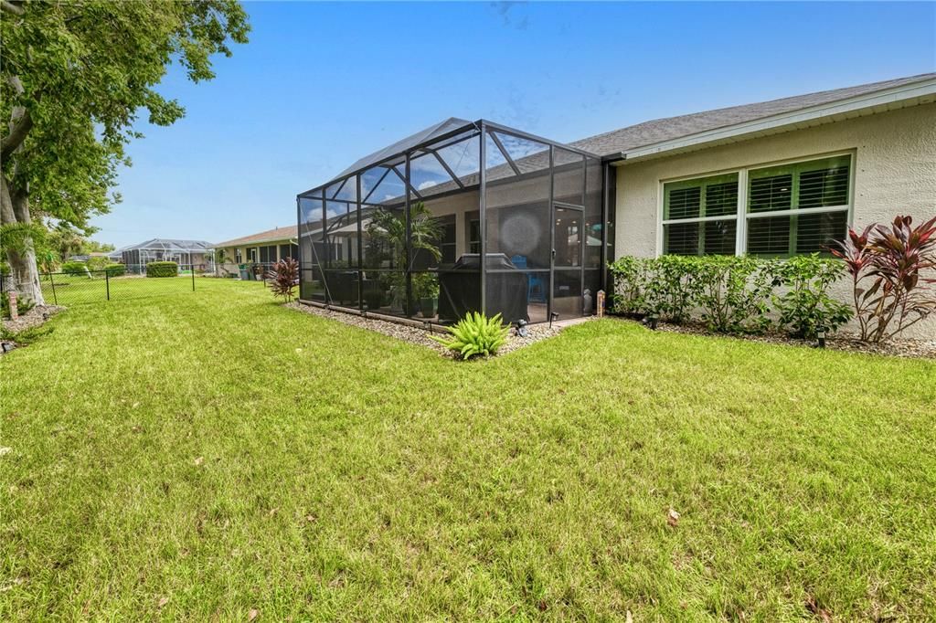 Landscaped, fenced back yard with extended, screened-pavered lanai for entertaining