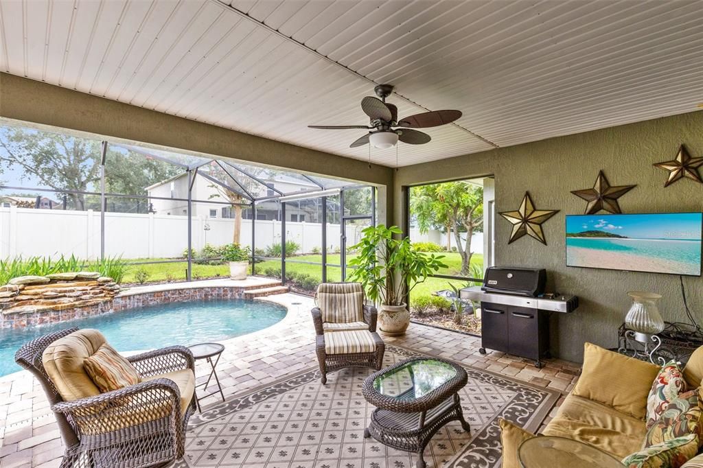 Welcome to your private outdoor oasis, a covered lanai overlooking the stunning pool with a tranquil waterfall feature, perfect for relaxation and entertaining.