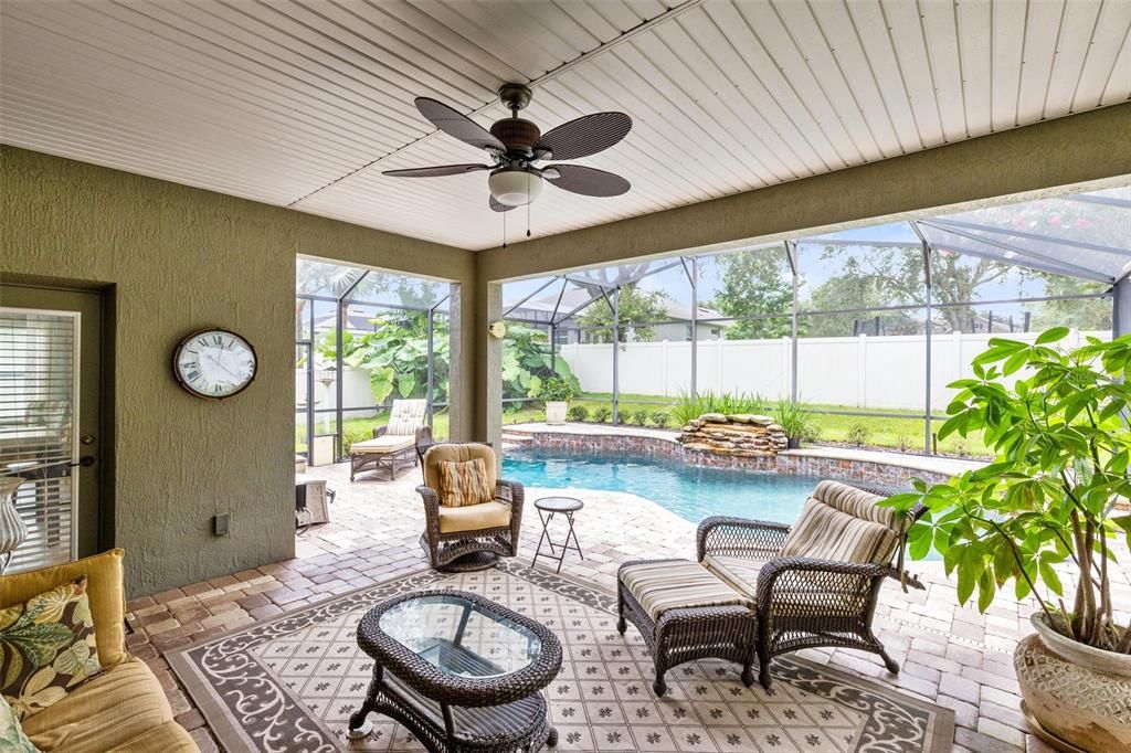 Welcome to your private outdoor oasis, a covered lanai overlooking the stunning pool with a tranquil waterfall feature, perfect for relaxation and entertaining.