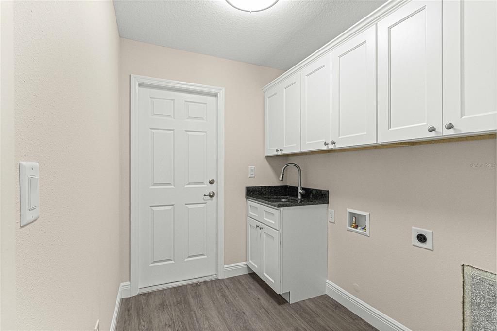 Laundry room with a granite countertop sin and plenty of cabinets for storage