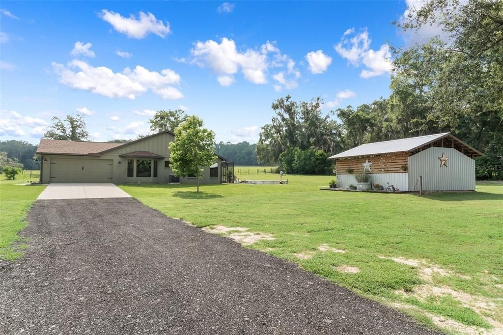 Driveway to garage and outdoor kitchen on right