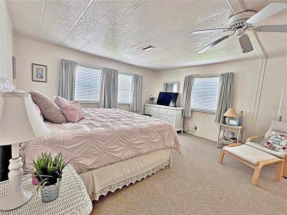 Primary bedroom with window treatments, ceiling fan, en suite bathroom