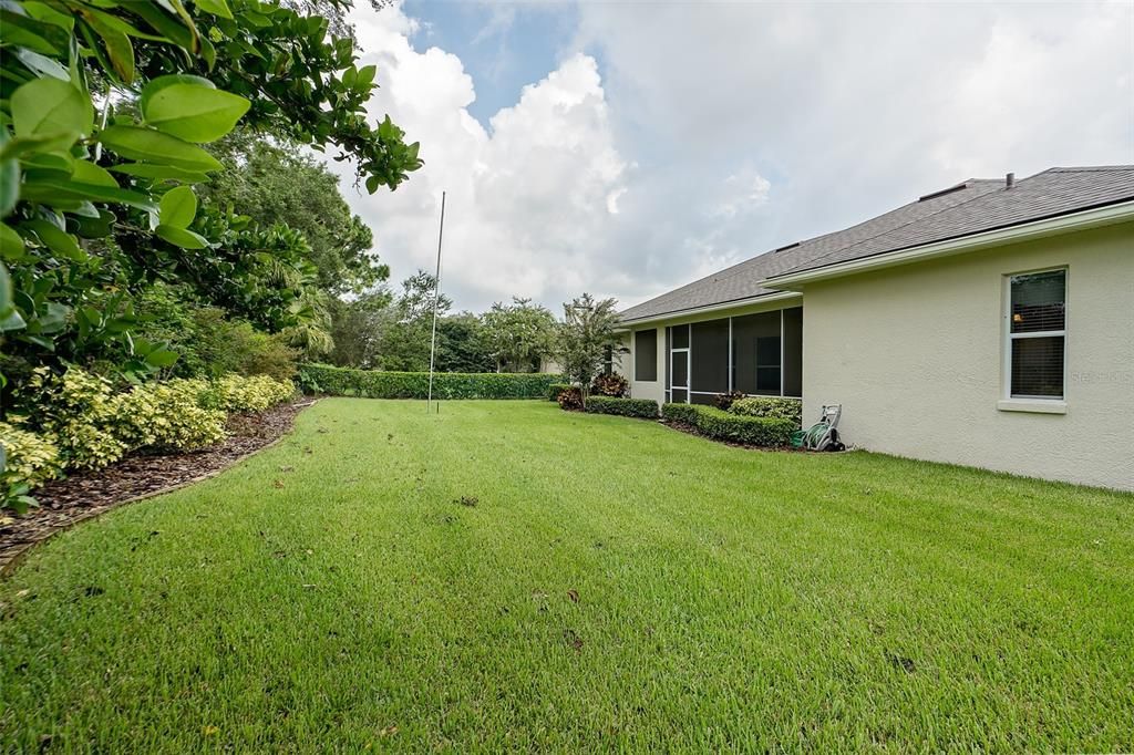 Beautiful lush landscaping in the backyard. The perimeter of the back yard is secured by a 4 foot green chain link fence.