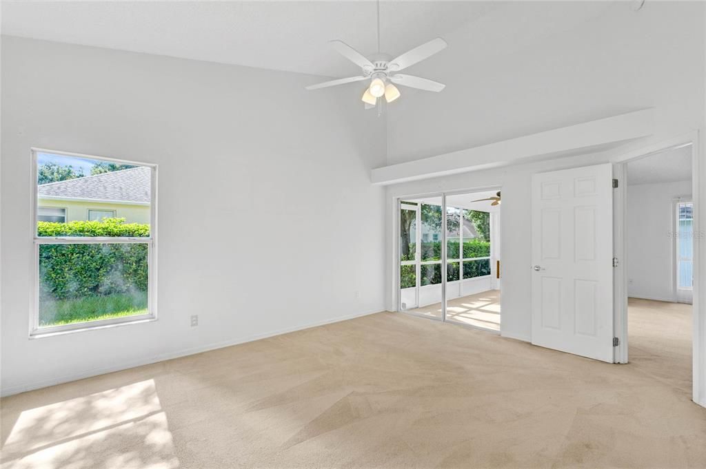 Primary bedroom has sliding glass doors leading to screened patio